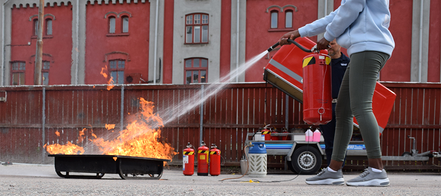 En person håller släcker en brand med en brandsläckare.