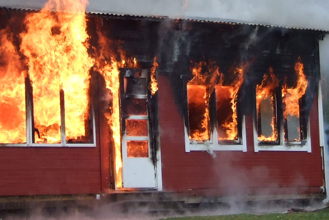 Brand i hus med lågor som slår ut från flera fönster.