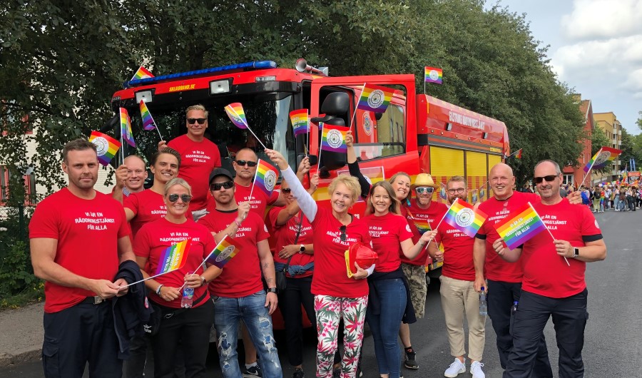 Glada medarbetare ppå Gävle Pride iklädda röda tröjor med texten Vi är en räddningstjänst för alla.