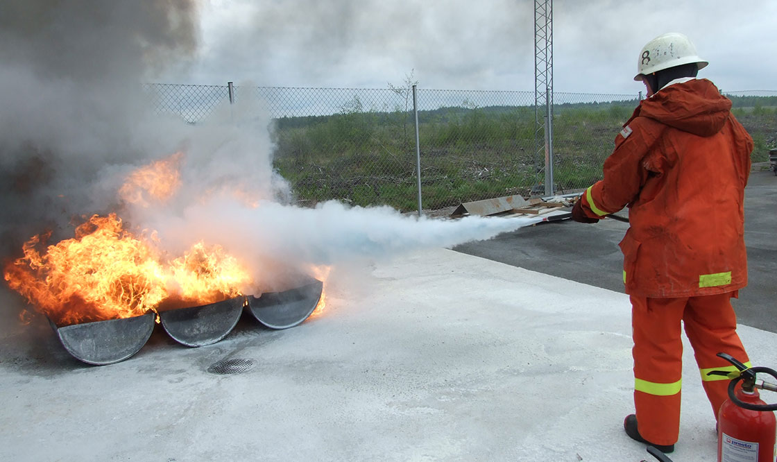 Brandman sprutar med brandsläckare på en eld.